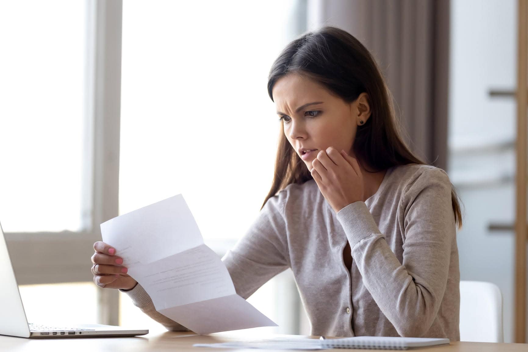 Vrouw leest brief en fronst haar wenkbrauwen.